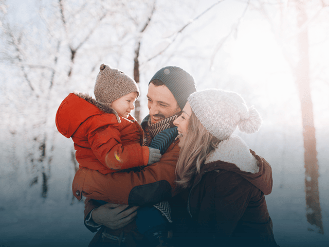 Familie som koser seg i snøen og ler sammen