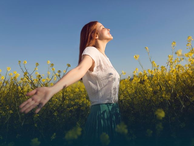 Glad jente som går i en blomstereng